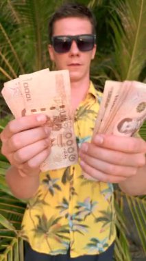 Tayland sahilinde Tayland Bahti sayan beyaz bir adam.