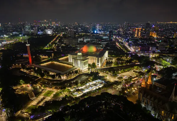 Aydınlatılmış Istiqlal Camii ve Jakarta şehrinin hava manzarası geceleri yükselişte, Endonezya