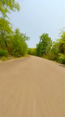 Hızlı FPV insansız hava aracı Tayland 'da güneşli bir yaz gününde yemyeşil ormanda dolambaçlı bir yolda uçuyor.