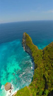 Endonezya, Bali 'deki Nusa Penida Adası' ndaki manzaralı uçurumlar ve turkuaz okyanus suları üzerinde sinematik FPV uçuşu