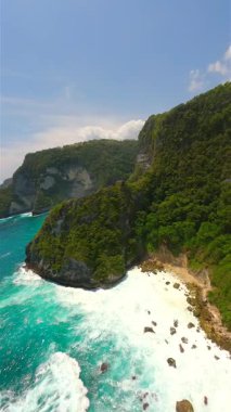 Endonezya, Bali 'deki Nusa Penida Adası' ndaki manzaralı uçurumlar ve turkuaz okyanus suları üzerinde sinematik FPV uçuşu