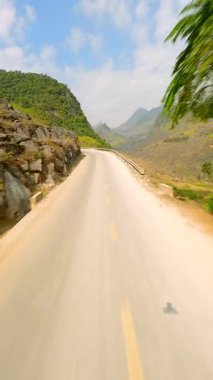 FPV insansız hava aracı HaGiang, Vietnam 'daki dolambaçlı dağ yolu ve manzaralı vadi üzerinde uçuyor.