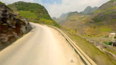 FPV insansız hava aracı HaGiang, Vietnam 'daki dolambaçlı dağ yolu ve manzaralı vadi üzerinde uçuyor.