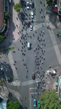 Ho Chi Minh City Saigon, Vietnam 'da motosiklet, scooter ve arabalarla dolu işlek cadde kavşağının yukarıdan aşağı görüntüsü.