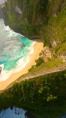 FPV insansız hava aracı Nusa Penida, Bali, Endonezya 'daki ikonik Kelingking Sahili' nde dramatik uçurumlar, beyaz kum plajları ve turkuaz okyanuslar üzerinde dalıyor..