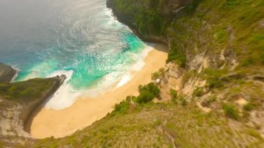 FPV insansız hava aracı Nusa Penida, Bali, Endonezya 'daki ikonik Kelingking Sahili' nde dramatik uçurumlar, beyaz kum plajları ve turkuaz okyanuslar üzerinde dalıyor..
