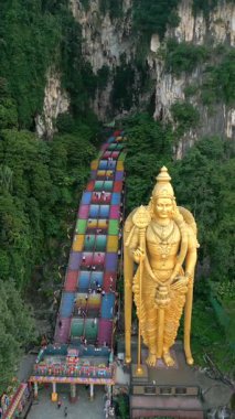 Kuala Lumpur, Malezya 'daki Batu Mağaraları ve altın Lord Murugan heykelinin havadan görünüşü. Renkli merdivenleri, kireçtaşı kayalıkları ve yemyeşil yeşillikleri olan ünlü dini mekan..