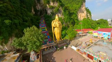 Malezya 'nın Kuala Lumpur kentindeki Batu Mağaraları ve altın Lord Murugan heykelinin FPV insansız hava aracı görüntüleri. Renkli merdivenleri, kireçtaşı kayalıkları ve yemyeşil yeşillikleri olan ünlü dini mekan..