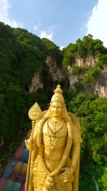 Malezya 'nın Kuala Lumpur kentindeki Batu Mağaraları ve altın Lord Murugan heykelinin FPV insansız hava aracı görüntüleri. Renkli merdivenleri, kireçtaşı kayalıkları ve yemyeşil yeşillikleri olan ünlü dini mekan..