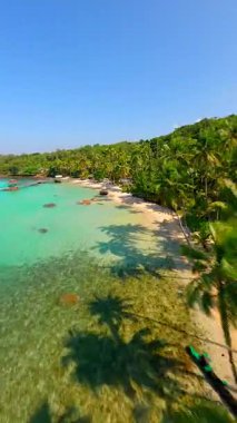 Tayland 'daki Koh Kood adasında, tropikal plajda, palmiye ağaçları, beyaz kum ve kristal berrak turkuaz deniz üzerinde uçan FPV uçağı. Egzotik kıyı şeridi ve cennet manzarasının havadan görünüşü.