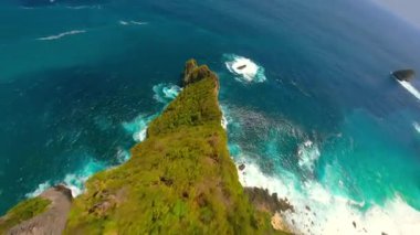 Endonezya, Bali 'deki Nusa Penida Adası' ndaki manzaralı uçurumlar ve turkuaz su boyunca sinematik FPV insansız uçuşu. Seyahat, doğa ve tropikal macera temaları için ideal hava manzarası.