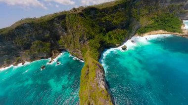 Endonezya, Bali 'deki Nusa Penida Adası' ndaki manzaralı uçurumlar ve turkuaz su boyunca sinematik FPV insansız uçuşu. Seyahat, doğa ve tropikal macera temaları için ideal hava manzarası.