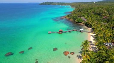 Tayland 'daki Koh Kood Adası' nda palmiye ağaçları, beyaz kum ve kristal berraklığında turkuaz deniz bulunan egzotik kıyı şeridi ve tropikal cennet plajı manzarası..