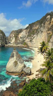 Kireçtaşı kayalıkları, turkuvaz okyanusu, beyaz kum ve Endonezya 'daki Nusa Penida Adası, Bali, Endonezya' daki palmiye ağaçlarının ikonik elmas sahili..