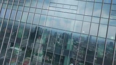 Cakarta, Endonezya 'nın kentsel ufuk çizgisini yansıtan cam gökdelen boyunca sinemalı FPV insansız hava aracı dalışı. Mimarlık, gayrimenkul ve şehir hayatı temaları için ideal.