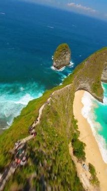 Dramatik uçurumlar, beyaz kum plajları ve Endonezya 'nın Nusa Penida kentindeki Kelingking Sahili' ndeki turkuaz okyanus üzerinde FPV insansız hava aracı uçuşu. Seyahat, yaz ve tropikal macera temaları için ideal.
