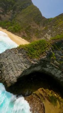 Beyaz kum plajı üzerinde uçan FPV İHA uçuşu ve Endonezya 'nın Nusa Penida kentindeki Kelingking Sahili' nde turkuaz okyanus. Seyahat, yaz ve tropikal macera temaları için ideal.