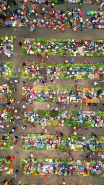 Aerial top-down view of vibrant Vietnamese market with fruits, vegetables, and people in conical hats. Colorful local culture and traditional street commerce in Southeast Asia.