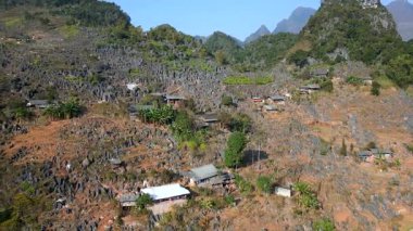Vietnam 'ın Ha Giang kentindeki dik kayalık yamaçlara inşa edilmiş geleneksel köyün hava manzarası. Kuzey dağlarındaki sivri kireçtaşı dağlarının arasına dağılmış uzak etnik evler.