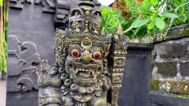 Endonezya, Bali 'deki Hindu tapınağında, koruma ve yerel maneviyatın sembolü olan, şişkin gözlü ve süslü geleneksel Balili muhafız heykelinin ayrıntılı görüntüsü..