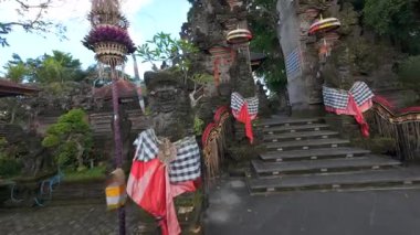 FPV İHA Bali Hindu tapınağına taş heykeller, penjor direkleri ve Endonezya 'daki kutsal kumaşlarla süslü tören kapısından girer. Ruhaniyete ve kültüre sembolik yolculuk.