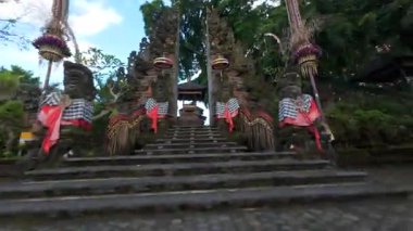FPV İHA Bali Hindu tapınağına taş heykeller, penjor direkleri ve Endonezya 'daki kutsal kumaşlarla süslü tören kapısından girer. Ruhaniyete ve kültüre sembolik yolculuk.