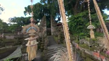 FPV insansız hava aracı Bali Hindu tapınağına taş heykeller ve Endonezya 'daki penjor direkleri ile tören kapısından girer. Ruhaniyete ve kültüre sembolik yolculuk.