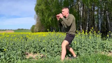 Atletik adam doğada dövüş sanatları yapıyor. Orman açıklarında dinamik tekmeler ve boks hareketleri sergiliyor. Vahşi doğada güç, kontrol ve disiplin.