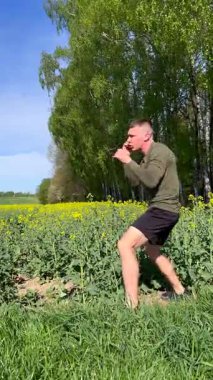 Atletik adam doğada dövüş sanatları yumrukları uyguluyor, dinamik boks hareketleri yapıyor vahşi doğada güç, odaklanma ve disiplin gösteriyor..