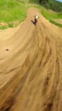 FPV insansız hava aracı yeşil kırsal ve orman boyunca motosiklet sürücüsünü takip ederek yaz güneşinde hızlı dönüşler, hız ve açık hava maceralarını yakalıyor..