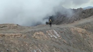 Endonezya 'daki Bromo Dağı volkan kraterinin kenarında duran kadının hava görüntüsü. Doğa kavramı, seyahat, macera ve nefes kesici manzaralar..
