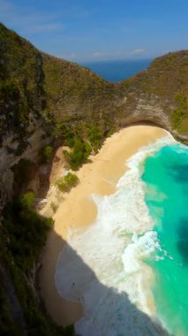 Dramatik uçurumlar, beyaz kum plajları ve Endonezya 'nın Nusa Penida kentindeki Kelingking Sahili' ndeki turkuaz okyanus üzerinde FPV insansız hava aracı uçuşu. Seyahat, yaz ve tropikal macera temaları için ideal.