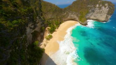 Dramatik uçurumlar, beyaz kum plajları ve Endonezya 'nın Nusa Penida kentindeki Kelingking Sahili' ndeki turkuaz okyanus üzerinde FPV insansız hava aracı uçuşu. Seyahat, yaz ve tropikal macera temaları için ideal.