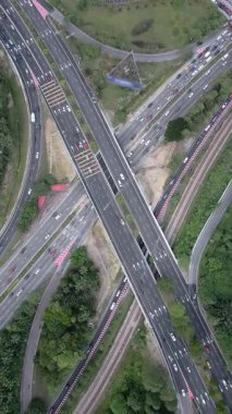 Malezya 'daki üst geçitler, trafik ve yeşillik ile çok yönlü otoyol kavşağının insansız hava aracı görüntüsü. Arabaları, yol işaretleri ve birden fazla şeridi olan modern ulaşım altyapısı.