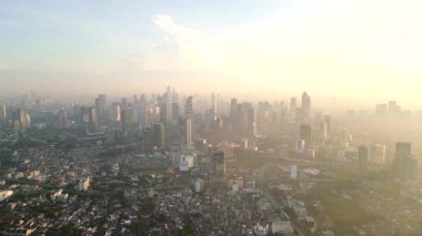 Jakarta şehrinin hava kirliliğiyle gün doğumunda gökyüzü manzarası. Yüksek binaların üzerinde sis bulunan Endonezya başkentinin yoğun kentsel manzarası.