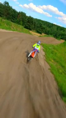 Motokros sürücüsünün toprak yolda döndüğü FPV 'nin sinematik yavaş çekim görüntüleri. Toz uçuşu, dinamik kıvrımlar ve doğal yaz manzarasında güçlü hareketler..