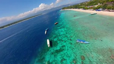 Tropikal Gili Trawangan, Endonezya üzerinde FPV insansız hava aracı uçuşu, turkuaz denizi, tekneler, beyaz kum plajı ve mercan resifleri. Ada cennetinin göz kamaştırıcı manzarası.