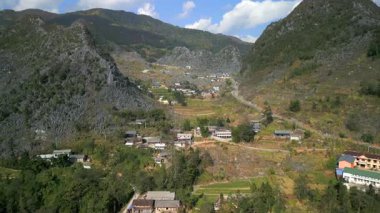 Kuzey Vietnam 'daki Ha Giang' daki dağ köyünün hava manzarası ve dolambaçlı yol. Kireçtaşı karst zirveleri, tarım arazileri ve dağınık evler eşsiz ve manzaralı kırsal alanlar yaratır..