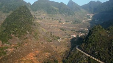 Kireçtaşı karst dağları, dolambaçlı vadi yolu ve Vietnam, Ha Giang 'daki dağınık köylerin hava manzarası dramatik manzaralar ve kırsal manzaralar sergiliyor..