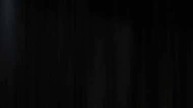 Takım elbiseli ve kravatlı bir adam mikrofonun önünde duruyor.