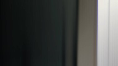 Takım elbiseli ve kravatlı bir adam pencerenin önünde duruyor.