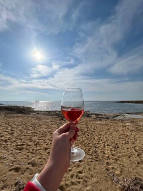 red wine in the hands of a woman on the beach