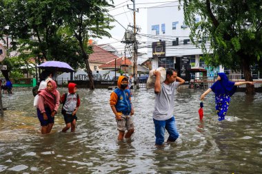 Semarang, Aralık 2022. Birkaç kişi evlerini su bastıktan sonra boşaltmaya hazırlanmak için yiyecek ve giysi dolu çuvallar taşıyor..