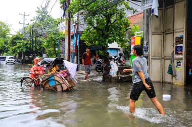Semarang, Aralık 2022. Bazı insanlar, Poncol tren istasyonundaki selde mahsur kalan insanları taşıyan pedikürleri itiyor..