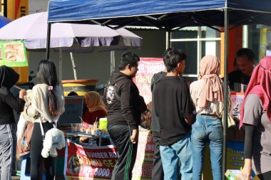 Kudus, December 2022. Photo of food and beverage vendors on the side of the road selling to a crowd of visitors and buyers in the main square of the Kudus city.