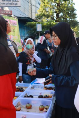 Kudus, December 2022. Photo of food and beverage vendors on the side of the road selling to a crowd of visitors and buyers in the main square of the Kudus city.