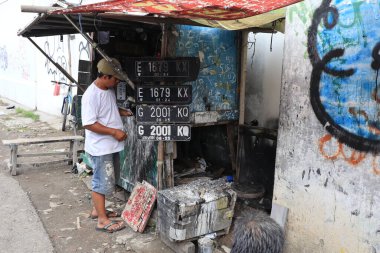 Tegal, Ocak 2023. Motosiklet plakası üreticisinin fotoğrafı. Neredeyse müşteriye ait olan plakayı boyuyor..