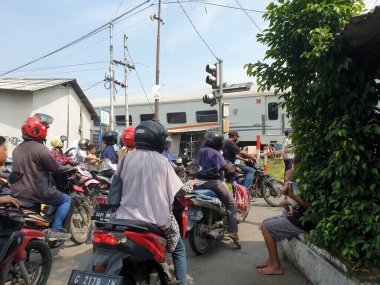 Tegal, Mayıs 2023. Bir grup motosikletli aracın fotoğrafı kavşakta durdu, çünkü tren raylarından geçen bir tren var..