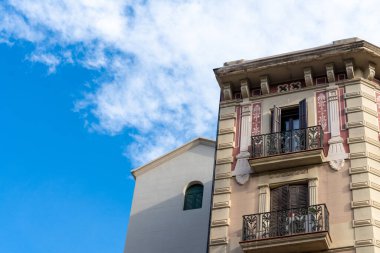 architectural details of the facade of a building on a background of blue sky and white clouds, Barcelona.
