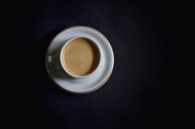 Hot cappuccino and coffee beans on a dark background